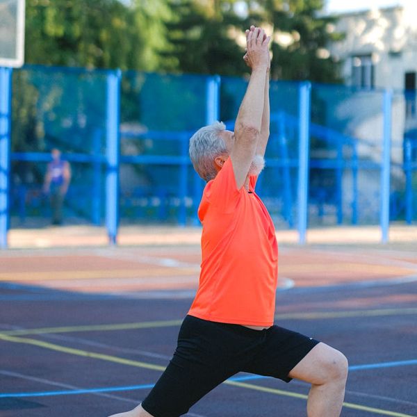 Person in an energetic yoga warrior pose against a simple background.